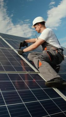 Mühendis, güneşli bir günde elektrikli matkap kullanarak güneş panelleri kurarken görülüyor. Güneş paneli kurulumu yenilenebilir enerjiyi kullanmak ve sürdürülebilir bir geleceği desteklemek için gereklidir