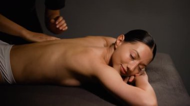 Güzel bir kadın, sakin bir spa ortamında rahatlatıcı bir sırt masajı sırasında rahatlar. Bir terapist nazikçe gerginliği atmak ve gençleşmeyi ve refahı arttırmak için çalışır.