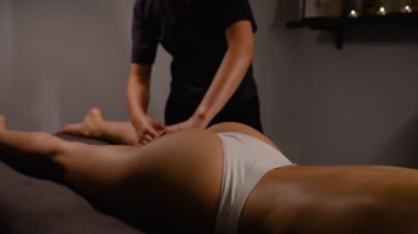 Profesyonel bir masaj terapisti huzurlu bir kaplıca ortamındaki bir kadına rahatlatıcı bir bacak ve kalça masajı sunar. Masaj kas gerilimini azaltmaya yardımcı olur ve genel rahatlık ve refahı arttırır.