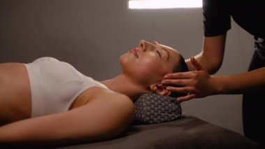 Masaj terapisti, sakin bir spa ortamındaki bir kadına stres önleyici kafa masajı yapar. Rahatlamasına ve gerilimi azaltmasına yardımcı olur. Bu rahatlatıcı deneyim rahatlamayı, dengeyi ve genel olarak iyi bir şekilde teşvik eder.