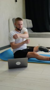 Bacağı kesilmiş ve protezi olan bir adam paspasın üzerinde egzersiz yapıyor. Rehabilitasyon sırasında fiziksel sağlığını ve hareketliliğini korumaya odaklanmış durumda.