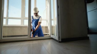 Güvenlik teçhizatında deneyimli bir teknisyen yeni takılmış bir pencereye köpük macunu sürerek yalıtım ve istikrar sağlıyor. Bu süreç enerji verimliliğini ve dayanıklılığını arttırır
