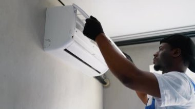 Bir Afrikalı Amerikalı teknisyen, temiz hava kalitesi ve verimliliğini artırmak için temizleme ya da yenileme amaçlı kirli bir filtreyi dikkatlice kaldırır.