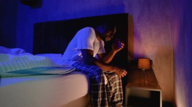 Afro-Amerikalı bir adam yatağında uykusuzluk ve depresyonla boğuşuyor. Mavi ve ılık ışık kasvetli, iç gözlemci bir atmosfer yaratır.
