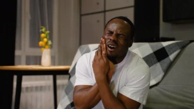 Şiddetli diş ağrısı çeken Afro-Amerikan bir adam çenesini tutuyor ve rahatsızlık veriyor. Bu sahne diş sorunlarının ve rahatlama ihtiyacının altını çiziyor.