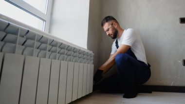 Profesyonel tesisatçı, ısıtma sisteminin bir parçası olarak dikkatli bir şekilde radyatör yerleştirir ve modern bir apartman dairesine optimal işlevsellik ve enerji verimliliği sağlar.