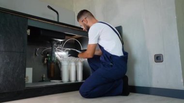 Profesyonel tesisatçı lavabonun altına ters osmoz su filtreleme sistemi kuruyor. Modern bir mutfak düzeninde temiz ve arıtılmış içme suyu sağlıyor.
