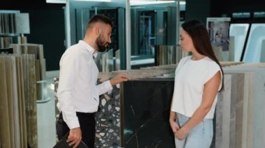 Sergi salonundaki bir danışman müşteriye doğru fayansı seçmesinde rehberlik eder. Çeşitli stil ve dokuları incelerler, müşterilerin ihtiyaçları için mükemmel bir eşleşme sağlarlar.