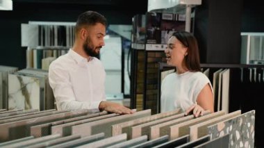 Bir müşteri, ideal uyumu bulmak için sergi danışmanı ile çeşitli fayans stilleri ve dokuları tartışır. Danışman kararı desteklemek için profesyonel rehberlik sunar