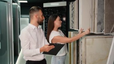 Bir kadın, sergi salonu danışmanından rehberlik alırken çeşitli fayans seçeneklerini değerlendirir. Danışman, projesinde en iyi seçimi yapmasına yardımcı olacak görüşleri sunar.