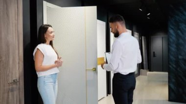 Bir müşteri, galeride bir satış temsilcisiyle görüşür, çeşitli kapı tasarımları ve ev dekorasyonu için en uygun seçenekleri araştırır.