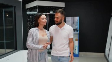 Bir çift, özel bir mağazadaki banyo tadilatları için çeşitli fayans tasarımları ve dekorasyonları araştırıyor.