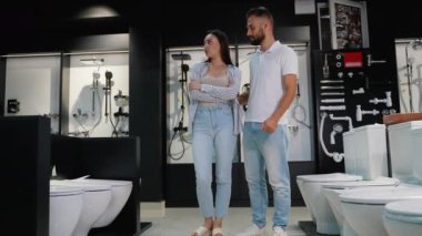 Bir çift, bir galeride çeşitli tuvalet ve tesisat tesisatlarını keşfediyor, banyo tarzlarını ve işlevselliklerini geliştirmek için dikkatlice eşyalar seçiyor.