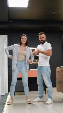 Komik bir çift banyo mobilyalarını keşfederken eğlenceli pozlar veriyor ve lüks bir galeride tesisat döşüyorlar, alışveriş deneyimlerine neşe katıyorlar.