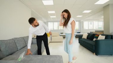 Arkadaş canlısı bir danışman, müşteriye mobilya galerisinde koltuk seçeneklerini değerlendirmesinde yardımcı olur. Konfor, tarz ve işlevsellik konusunda rehberlik eder.