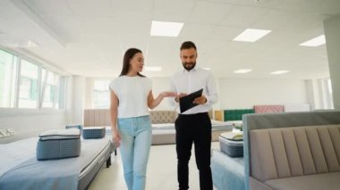 Müşteri yatak ve yatak seçeneklerini bir satış danışmanıyla gözden geçirir ve mükemmel bir uyku için en uygun özellikleri ve destek ihtiyaçlarını tartışır.