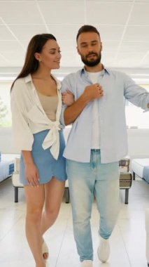 Mutlu bir çift mobilya mağazasındaki bir satış etkinliği sırasında yatak seçeneklerini kontrol eder. Evleri için en uygun yatağı bulmak için rahatlık seviyelerini hevesle test ederler.