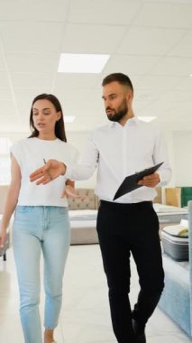 Dost canlısı bir mobilya danışmanı, müşteriye galeride seçenekleri tartışırken ve evi için mükemmel parçaları bulması için ona rehberlik ederken yardımcı olur.