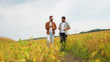 İki çiftçi yemyeşil bir soya tarlasında yürüyor, bitkileri tutuyor ve ekinlerin büyümesini tartışıyor. Sahne, sürdürülebilir tarımda işbirliği ve adanmışlığı yakalıyor