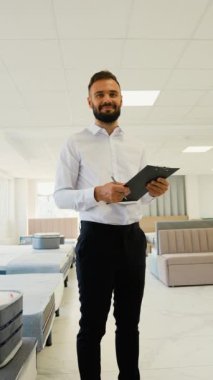 Mobilya mağazasındaki profesyonel bir satıcı ürün detaylarını bir panoda kontrol eder, şık bir galeride müşterilere seçimlerinde yardımcı olmaya hazırdır.
