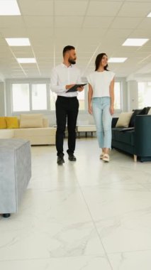 Arkadaş canlısı bir danışman, müşteriye mobilya galerisinde koltuk seçeneklerini değerlendirmesinde yardımcı olur. Konfor, tarz ve işlevsellik konusunda rehberlik eder.