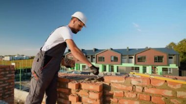 Kendini adamış bir inşaatçı modern bir konak inşa ederken tuğlaları dikkatlice yerleştirir. Kaliteli evlerin temelini ustalık ve işçilik şekillendirir