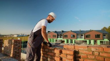 Yetenekli bir inşaatçı, duvarların hizalanmasını ölçerken tuğlaları modern bir konut projesi sahasının hassasiyetini güvence altına alarak, bir seviye aracıyla dikkatlice yerleştirir.