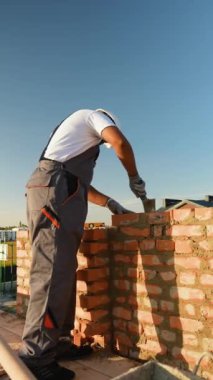 Profesyonel bir müteahhit, modern bir konut inşa ederken tuğla döşeyip harç döşeyerek titizlikle çalışır.