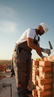 Hintli inşaat işçisi sağlam bir yapı oluşturmak için tuğla örüyor. Video, inşaat alanında kendini adamışlık ve beceri kaydediyor.