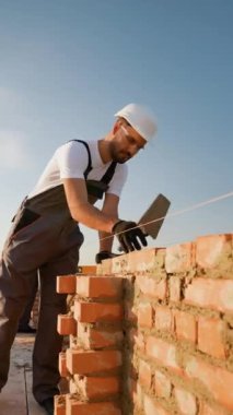Kendini adamış bir inşaatçı modern bir konak inşa ederken tuğlaları dikkatlice yerleştirir. Kaliteli evlerin temelini ustalık ve işçilik şekillendirir