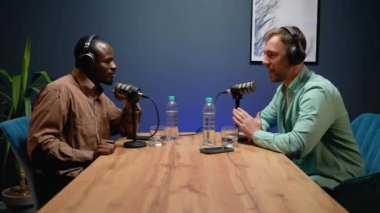 İki blogcu, Afrikalı Amerikalı ve Kafkasyalı profesyonel bir stüdyoda podcast kaydı sırasında güncel haberleri tutkuyla tartışıyorlar.