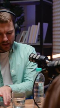 Bir podcast sunucusu mikrofona konuşuyor ve modern bir stüdyoda canlı kayıt sırasında düşünceli bir konuşma yapıyor.