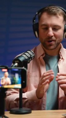 Gülümseyen bir blogcu profesyonel ses ekipmanı ve akıllı telefonuyla canlı yayın yapıyor. Çarpıcı kurgu, anın heyecanını yakalar.