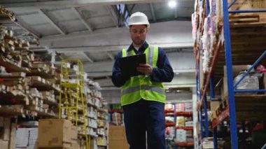 Güvenlik teçhizatı kullanan bir depo çalışanı envanteri titizlikle gözden geçirir ve depodaki stokların doğru izlenmesini ve düzenlenmesini sağlar.