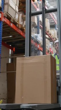 Depo çalışanı büyük bir kutuyu kaldırmak için forklift kullanıyor, yoğun bir depolama tesisinde verimli bir işleme ve organizasyon sağlıyor.