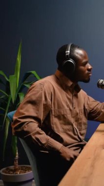 Afrikalı Amerikalı blogcu modern bir stüdyoda canlı yayında heyecanlı bir konuşma yaparak profesyonel ses ekipmanları ve dinamik bir titreşim sergiliyor.