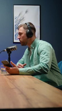 Bir podcast sunucusu mikrofona konuşuyor ve modern bir stüdyoda canlı kayıt sırasında düşünceli bir konuşma yapıyor.