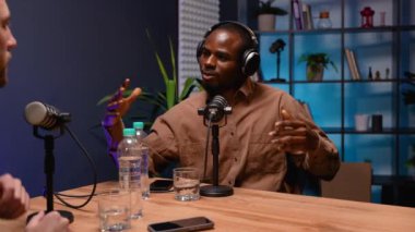 Bir podcast sunucusu, kayıt sırasında anlaşılır sorular sorarak, dinamik ve etkileşimli bir konuşma yaratarak, misafirle aktif bir şekilde iletişim kurar.