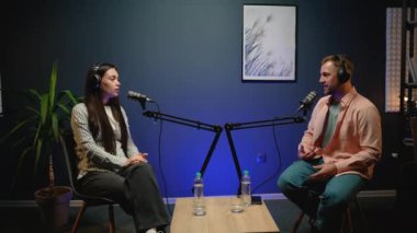 İki blogcu, profesyonel bir stüdyoda podcast kaydı sırasında güncel haber konularını tutkuyla tartışıyor.