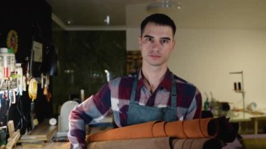 Bir deri işçisi, yüksek kaliteli el yapımı malların yapımında kullanılan materyallerin altını çizerek, bir atölyede kaliteli deri rulolarını gururla sergiler.
