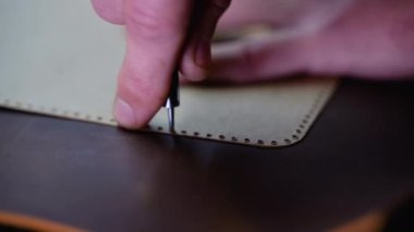 Deriyi delinmiş bir şablon ve bir teneke kullanarak işaretleyen bir zanaatkârın detaylı yakın çekimi. Görüntü hassasiyet ve ustalık tekniklerini vurgular.