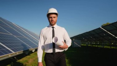 Güneş enerjisi santralinde yürüyen, yenilenebilir enerji, sürdürülebilirlik ve yeşil teknolojiye yatırım yapan bir yatırımcı.