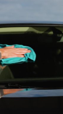 Profesyonel bir oto yıkama işçisi arabanın kaputunu titizlikle mikrofiber bezle parlatarak parlak ve lekesiz bir son sağlar. Üst düzey servise adanmışlık