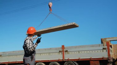 İşçi inşaat alanındaki büyük beton levhanın kaldırılmasını ve yerleştirilmesini dikkatle denetliyor.