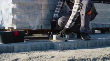 Bir işçi inşaat sahasına beton kaldırım döşemek için ustalıkla çekiç kullanır. Ahırın yanında sağlam ve dayanıklı bir yol sağlar.