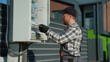 Bir elektrikçi, bir kasaba evinin yakınındaki elektrik panelini incelerken elektrik şoku geçirir ve elektrikle çalışmanın risklerini vurgular.