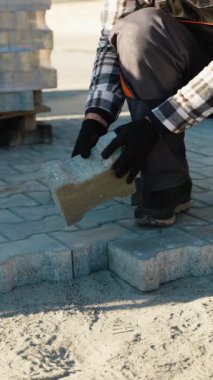 İnşaat alanına beton kaldırımlar döşeyen yetenekli bir işçi. Etrafı malzeme yığınlarıyla çevrili. İnşaat ve kaldırım endüstrisi temaları için mükemmel bir video