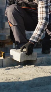 Yazlık evin yakınına beton bloklar yerleştiren bir kaldırım işçisi. Açık alanı, dayanıklı yollar için hassasiyet ve kaliteyle şekillendiren odaklanmış bir işçi.