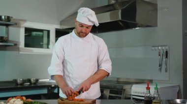 Profesyonel bir mutfakta aşçı sağlıklı bir yemek hazırlamak için tahtadan taze havuç kesiyor..