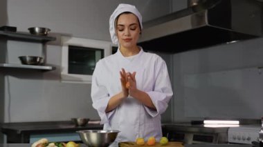 Beyaz üniformalı kadın bir şef taze malzemeler ve aletlerle çevrili modern bir mutfakta renkli falafel topları yuvarlıyor..